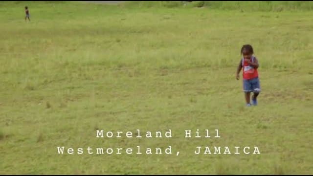 A young child crossing the wide grass field beside Moreland Hill Primary School in Westmoreland